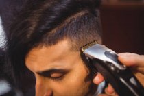 Мужчина стрижёт волосы триммером в парикмахерской — стоковое фото