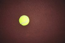 Tennis ball on brown ground in sport court — Stock Photo