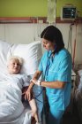 Infermiera che controlla la pressione sanguigna del paziente anziano in ospedale — Foto stock