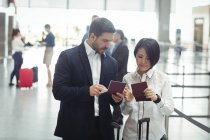 Business man and woman checking their passports in airport terminal — Stock Photo