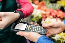 Cropped image of Woman making payment through smart watch in garden centre — Stock Photo
