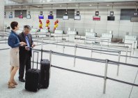 Gente de negocios esperando en el mostrador de facturación con equipaje en la terminal del aeropuerto - foto de stock