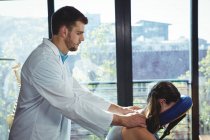 Fisioterapeuta dando masaje de espalda a la paciente femenina en la clínica - foto de stock