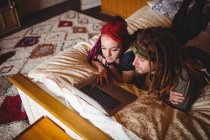 Vue grand angle du jeune couple en utilisant un ordinateur portable sur le lit à la maison — Photo de stock