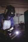 Female welder working on piece of metal in workshop — Stock Photo