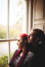Junges Paar umarmt sich beim Blick durchs Fenster zu Hause — Stockfoto