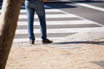 Sección baja del hombre caminando por la calle a la luz del día - foto de stock