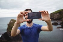 Man taking selfie from mobile phone on cliff — Stock Photo