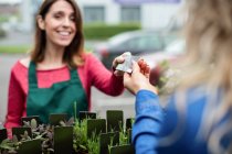 Женщина платит кредитной картой флористу в садовом центре — стоковое фото