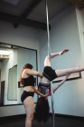 Instructor que ayuda a la bailarina de polo con la pose correcta en el gimnasio - foto de stock