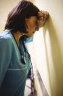 Depressed nurse leaning against wall in hospital — Stock Photo