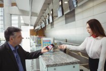 Бизнесмен, показывающий мобильный посадочный талон сотрудникам авиакомпании при регистрации на рейс — стоковое фото