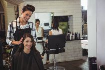 Sorridente parrucchiere femminile che lavora sul cliente nel salone di parrucchiere — Foto stock