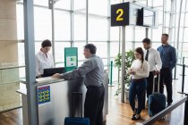 Пасажири чекають черги на стійці реєстрації в терміналі аеропорту — стокове фото