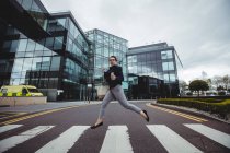 Longitud completa de la mujer de negocios corriendo fuera del edificio en la carretera - foto de stock