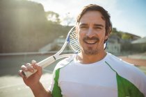 Счастливый человек, стоящий в суде с теннисной ракеткой — стоковое фото