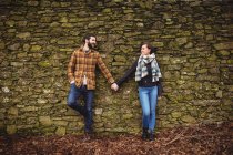 Счастливая пара прислонилась к каменной стене — стоковое фото