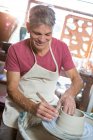 Счастливый мужчина гончар делает горшок в мастерской керамики — стоковое фото