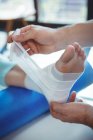 Imagem recortada de terapeuta masculino colocando bandagem no pé paciente feminino na clínica — Fotografia de Stock