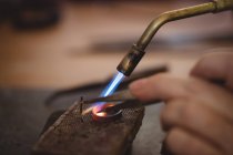 Cropped image of Goldsmith crafting ring by burner in workshop — Stock Photo