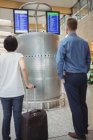 Voyageurs regardant les écrans d'affichage de départ et d'arrivée à l'aéroport — Photo de stock