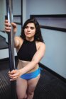 Vue grand angle de la belle danseuse pôle pratiquant la pole dance dans le studio de fitness — Photo de stock
