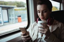 Beautiful woman using cellphone by window in train — Stock Photo