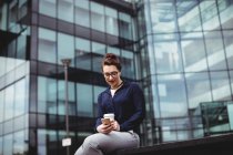 Junge Frau mit Handy gegen modernes Bürogebäude — Stockfoto