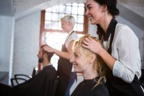 Усміхнене волосся стиліст масажує клієнтське волосся в салоні — стокове фото