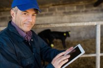 Портрет впевненого фермерського робітника з використанням цифрового планшета в сараї — стокове фото