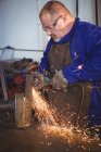 Сварщик распиливания металла с электрическим инструментом в мастерской — стоковое фото
