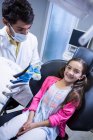 Dentist holding mouth model next to smiling young patient in clinic — Stock Photo