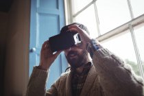 Young man using virtual glasses at home near window — Stock Photo