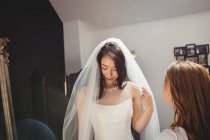 Жінка намагається на весільній сукні в студії за допомогою креативного дизайнера — стокове фото