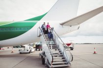 Passengers exit airplane down stairs at airport — Stock Photo