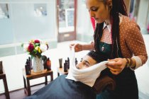Barbeiro aplicando toalha quente no rosto do cliente na barbearia — Fotografia de Stock