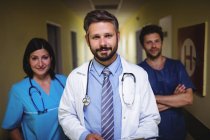 Squadra di medici in piedi e guardando in camera nel corridoio dell'ospedale — Foto stock