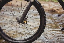 Cropped image of bicycle wheel in stream — Stock Photo