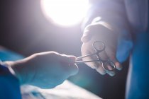 Chirurghi che danno forbici operatorie a collega in sala operatoria in ospedale — Foto stock