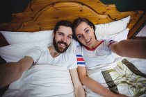 Portrait of couple lying together on bed at bedroom — Stock Photo