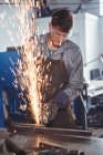 Schöner Schweißer schneidet Metall mit Elektrowerkzeug in Werkstatt — Stockfoto