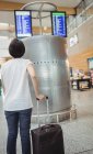 Frau betrachtet Anzeigetafel für Abflug und Ankunft im Flughafen — Stockfoto