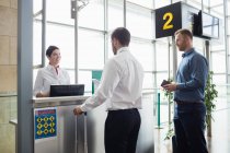 Homem que dá o passaporte ao funcionário do check-in da companhia aérea no balcão de check-in do aeroporto — Fotografia de Stock