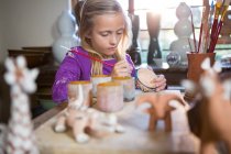 Aufmerksame Mädchen malen in Töpferwerkstatt auf Schale — Stockfoto
