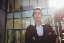 Уверенная деловая женщина со скрещенными руками стоит снаружи офисного здания — стоковое фото