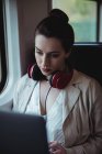 Жінка використовує ноутбук, сидячи біля вікна в поїзді — стокове фото