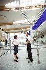 Пилот и стюардесса взаимодействуют друг с другом в терминале аэропорта — стоковое фото