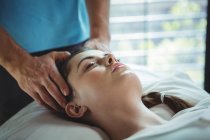 Мужской физиотерапевт делает женскому пациенту массаж головы в клинике — стоковое фото
