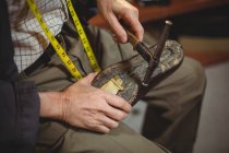 Mãos de sapateiro martelando em um sapato na oficina — Fotografia de Stock