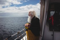 Рыбак держит бинокль и смотрит на море с лодки — стоковое фото